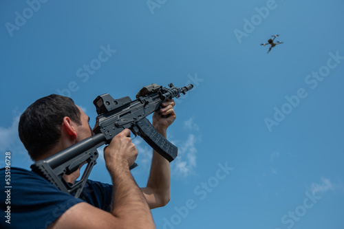 Caucasian man shoots a flying drone with a rifle.