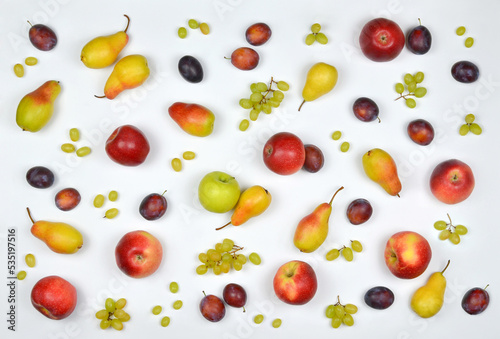 White background with fresh, ripe isolated fruits : plums, apples, pears and branches and separate berries of green grapes . Autumn colorful pattern from different fresh fruits . top view flat lay.
