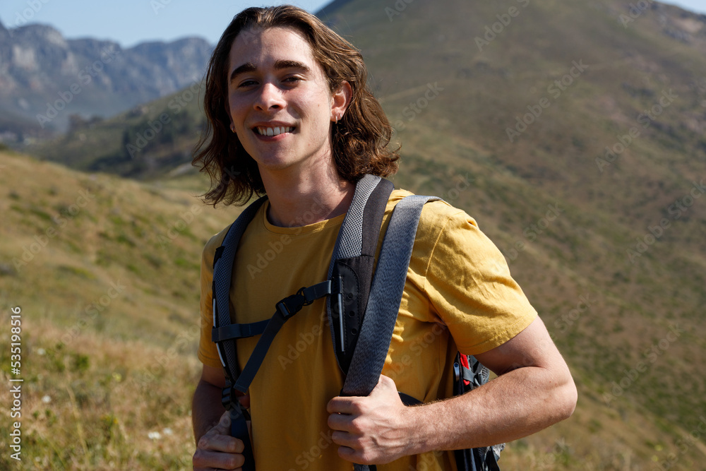Portrait of young male caucasian hiker with long hair smiling at camera