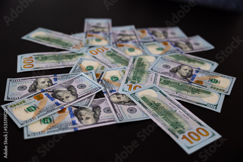 Fan of paper one hundred dollars banknotes on wooden table. Heap of money