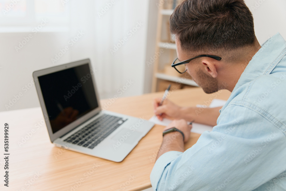 View from back. Serious focused handsome businessman work online using laptop in home office interior. Copy space. Distance remote work communication. Gadget addiction View from back. Serious focused handsome businessman work online using laptop in home office interior. Copy space. Distance remote work communication. Gadget addiction