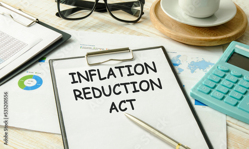 Inflation Reduction Act text on sticky with pen ,calculator and glasses on a beige background photo