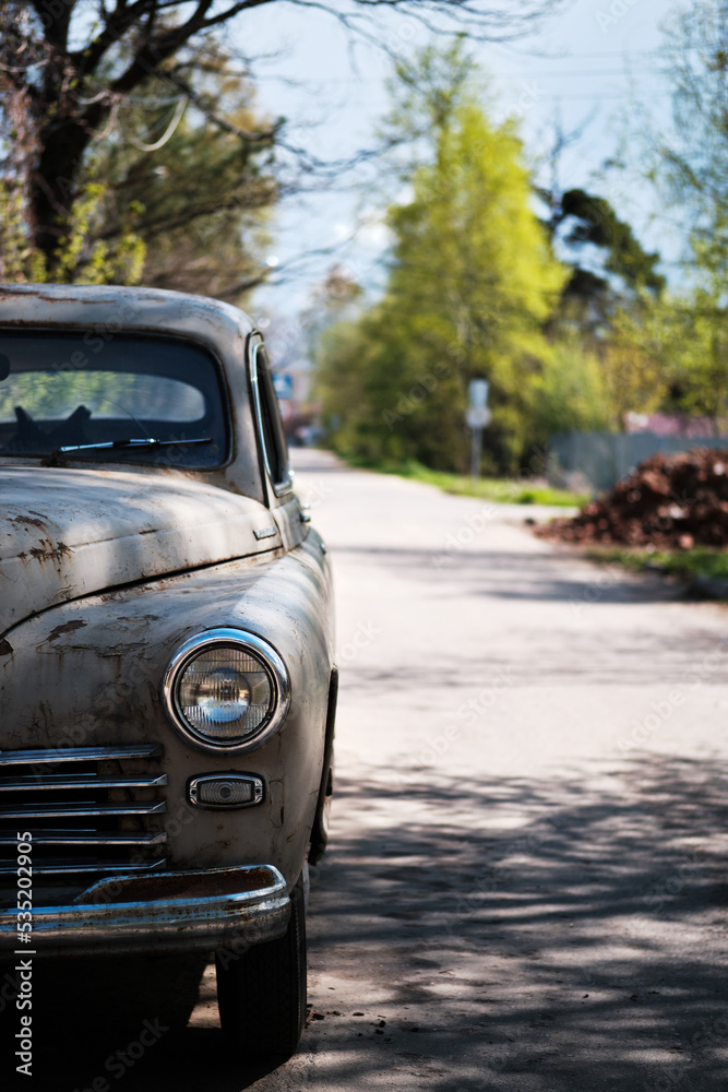 Fragment of an old passenger car on a suburban road. An old rusty automobile. Selective focus.