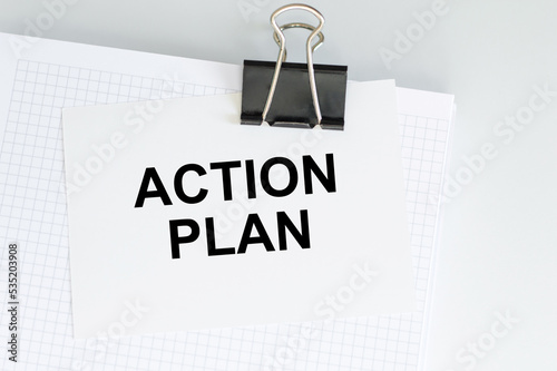 ACTION PLANNING card on a notepad clip on a light desk, business concept