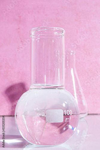 Transparent glass flask on a pink background. science research chemistry banner laboratory background.