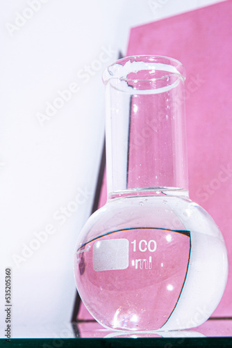 Transparent glass flask on a pink background. science research chemistry banner laboratory background.