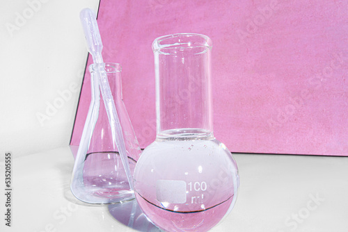 Transparent glass flask on a pink background. science research chemistry banner laboratory background.