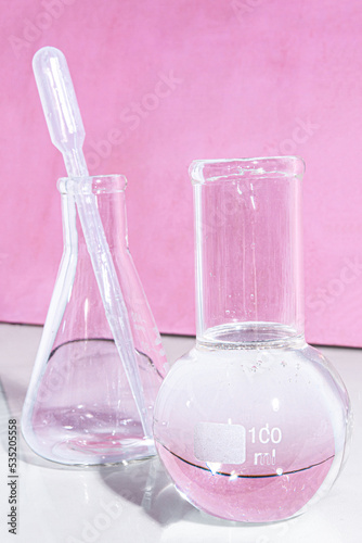 Transparent glass flask on a pink background. science research chemistry banner laboratory background.