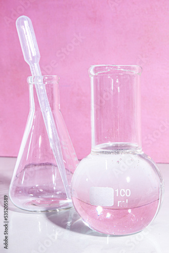 Transparent glass flask on a pink background. science research chemistry banner laboratory background.