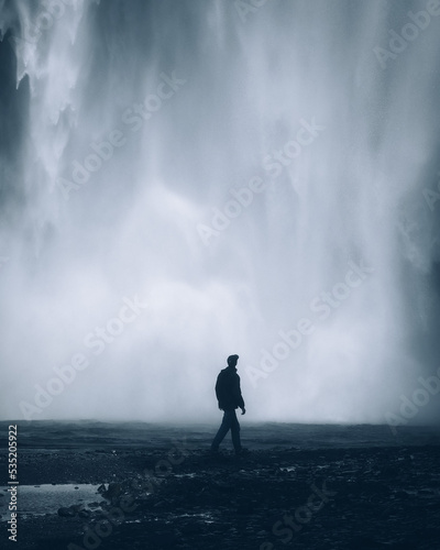 moody waterfall in iceland with person in front