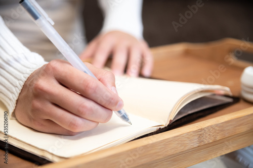 close-up, female hands write with a pen in a paper notebook, work or study from home remotely