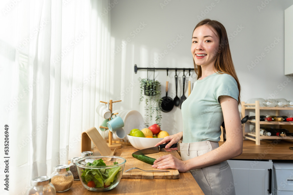 Young Caucasian attractive woman cook green salad in kitchen at home. 