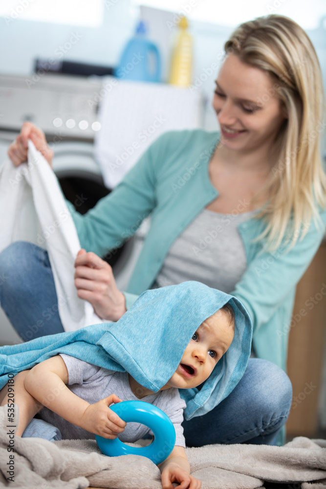 Fototapeta premium mother and baby loading clothes into washing machine