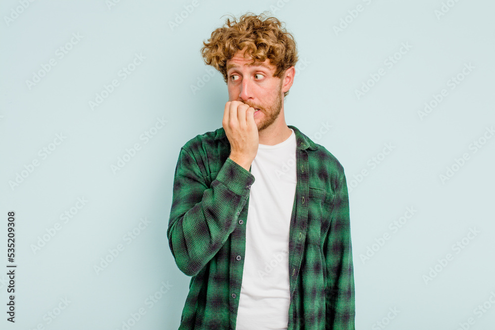 Young caucasian man isolated on blue background biting fingernails, nervous and very anxious. Young caucasian man isolated on blue background biting fingernails, nervous and very anxious.