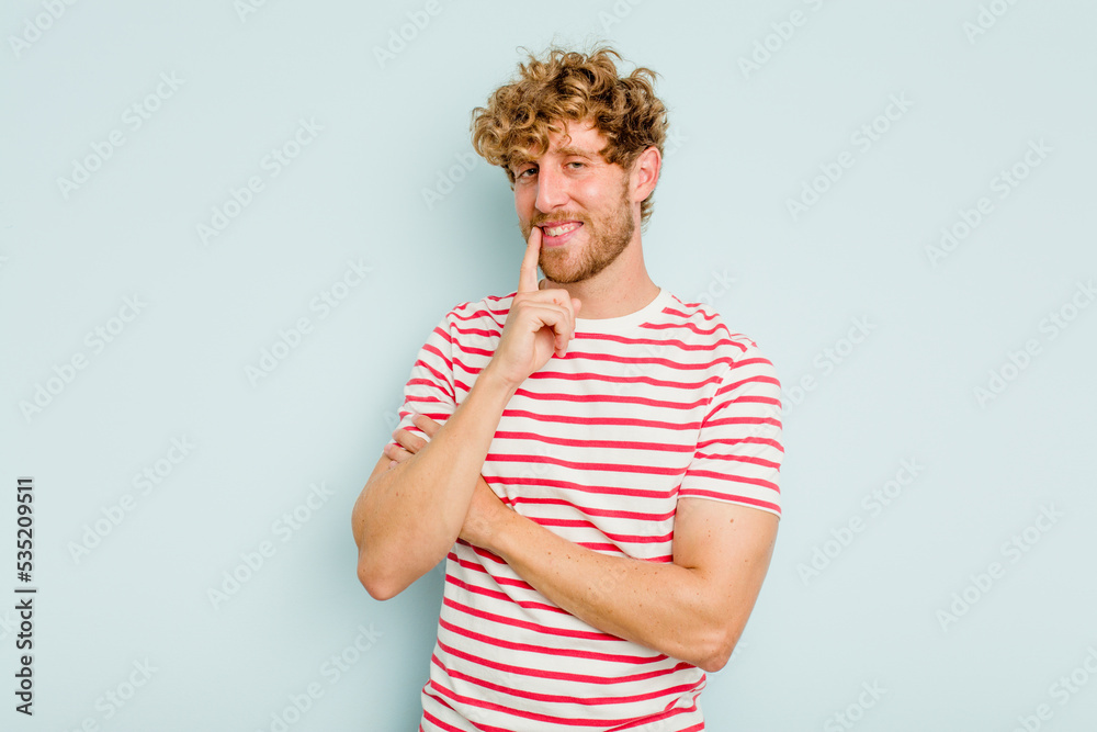 Young caucasian man isolated on blue background smiling happy and confident, touching chin with hand. Young caucasian man isolated on blue background smiling happy and confident, touching chin with hand.