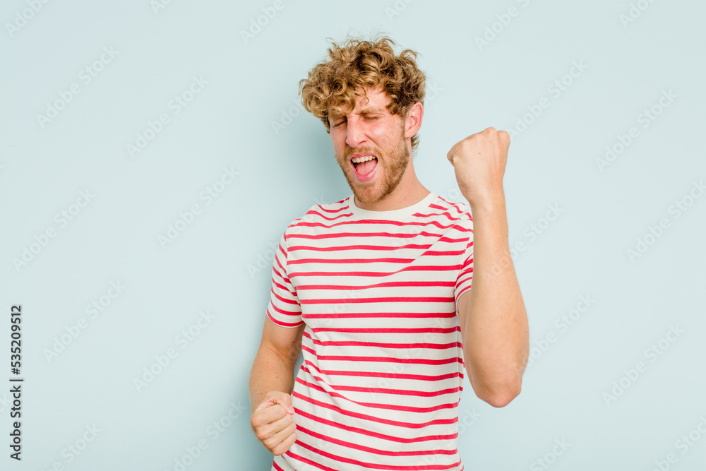 Young caucasian man isolated on blue background cheering carefree and excited. Victory concept. Young caucasian man isolated on blue background cheering carefree and excited. Victory concept.