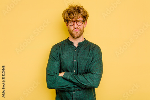 Фотография Young caucasian man isolated on yellow background frowning face in displeasure, keeps arms folded