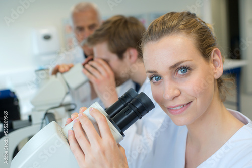 beautiful female medical doctor using a microscope