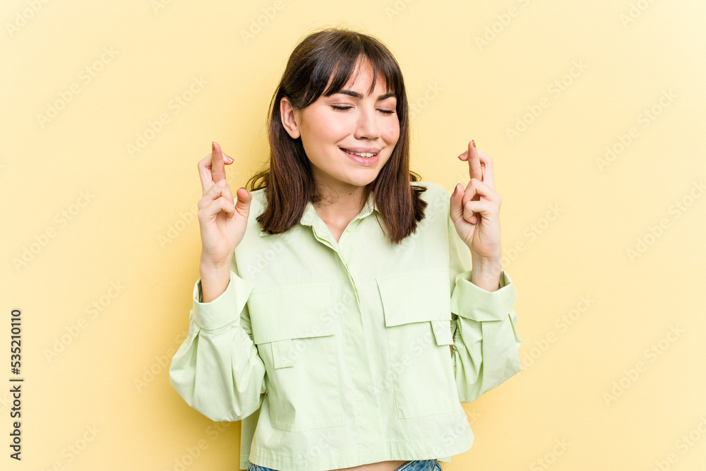 Young caucasian woman isolated on yellow background crossing fingers for having luck Young caucasian woman isolated on yellow background crossing fingers for having luck