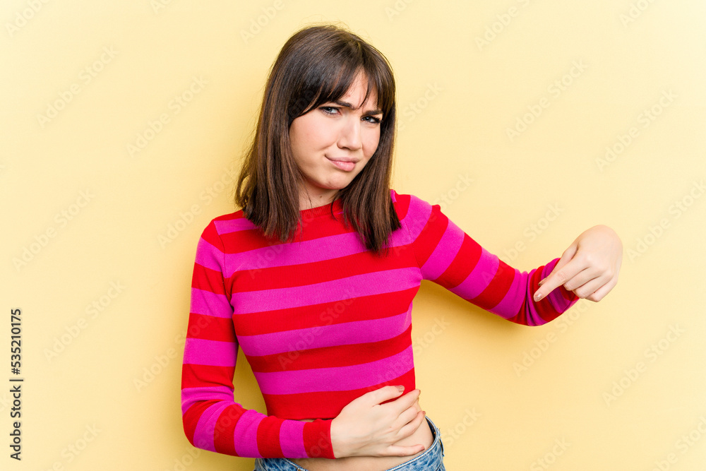 Young caucasian woman isolated on yellow background having a liver pain, stomach ache. Young caucasian woman isolated on yellow background having a liver pain, stomach ache.