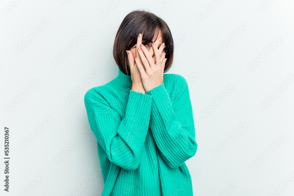 Young caucasian woman isolated on white background blink at the camera through fingers, embarrassed covering face. Young caucasian woman isolated on white background blink at the camera through fingers, embarrassed covering face.