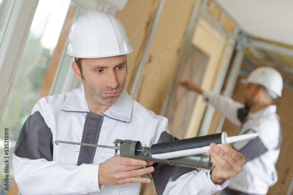 construction worker recharging caulking gun inside new building construction worker recharging caulking gun inside new building