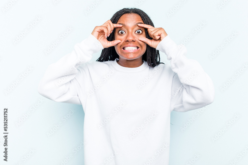 Young African American woman with braids hair isolated on blue background keeping eyes opened to find a success opportunity. Young African American woman with braids hair isolated on blue background keeping eyes opened to find a success opportunity.