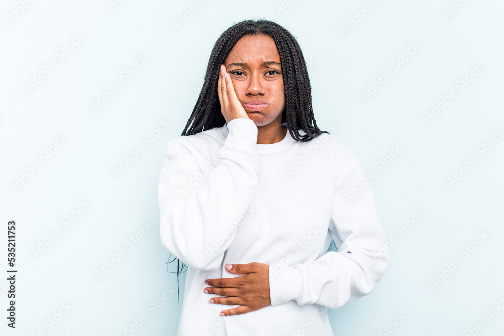Young African American woman with braids hair isolated on blue background blows cheeks, has tired expression. Facial expression concept. Young African American woman with braids hair isolated on blue background blows cheeks, has tired expression. Facial expression concept.