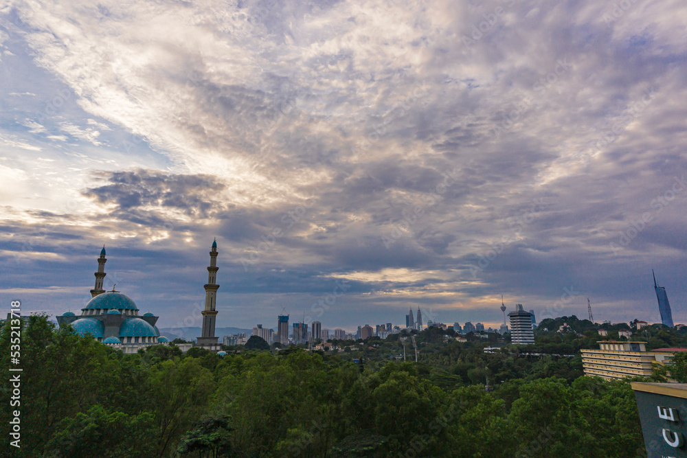Unique structure of Mosque (Masjid WIlayah) during cloudy sunrise with KL cityscape background