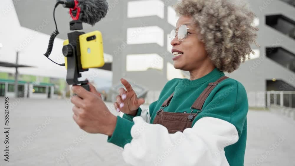 Modern African American Woman influencer recording a video vlog with smartphone in the city for online streaming apps