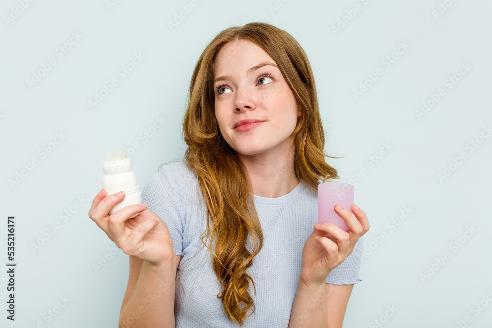 Young caucasian woman holding deodorant isolated on blue background Young caucasian woman holding deodorant isolated on blue background