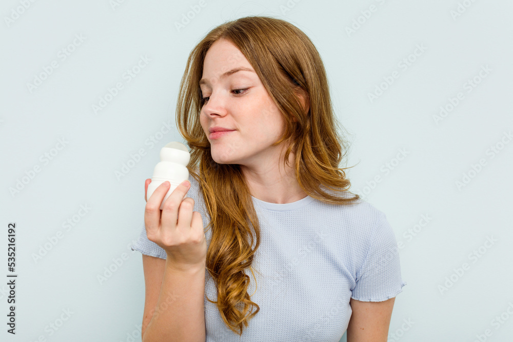 Young caucasian woman holding deodorant isolated on blue background Young caucasian woman holding deodorant isolated on blue background