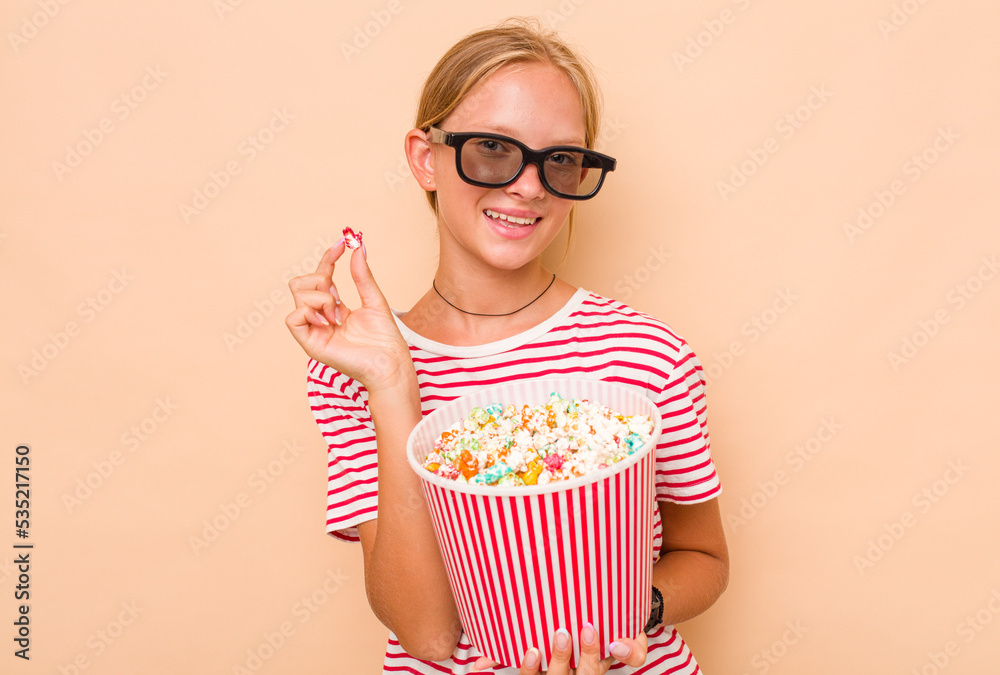 Little caucasian girl eating popcorn isolated on beige background