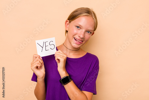 Little caucasian girl holding yes placard isolated on beige background