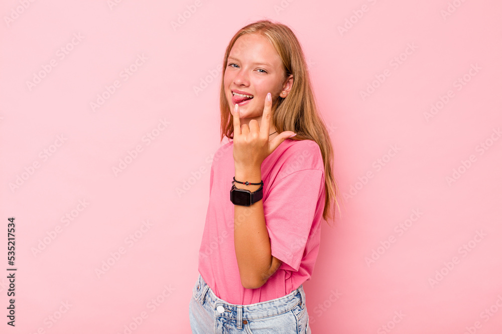 Caucasian teen girl isolated on pink background showing rock gesture with fingers Caucasian teen girl isolated on pink background showing rock gesture with fingers