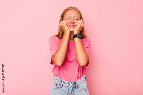 Caucasian teen girl isolated on pink background whining and crying disconsolately.