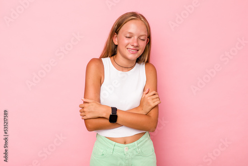 Caucasian teen girl isolated on pink background laughing and having fun.