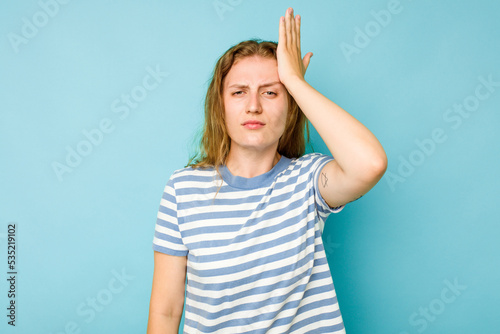 Young caucasian woman isolated on blue background forgetting something, slapping forehead with palm and closing eyes.