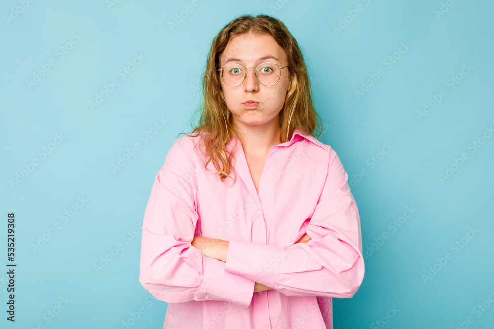 Young caucasian woman isolated on blue background blows cheeks, has tired expression. Facial expression concept. Young caucasian woman isolated on blue background blows cheeks, has tired expression. Facial expression concept.
