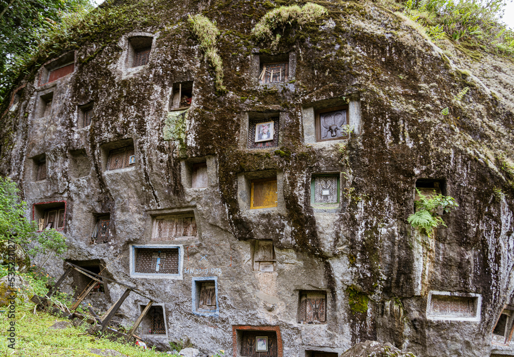 Java, Indonesia, June 13, 2022 - Prestigious Toraja citizens are buried in manually carbed out slots in a rock hillside. Java, Indonesia, June 13, 2022 - Prestigious Toraja citizens are buried in manually carbed out slots in a rock hillside.