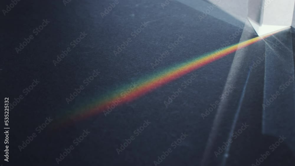 Close up shot of light being dispersed through glass prism and split into spectrum of rainbow colors