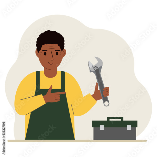 A man holds an adjustable wrench in his hand and a tool box next to it. The concept of technical repair or service.