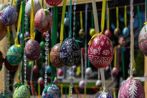 Painted eggs hang from the branches of the Easter tree. The focus is on a yellow egg painted by children by hand.
