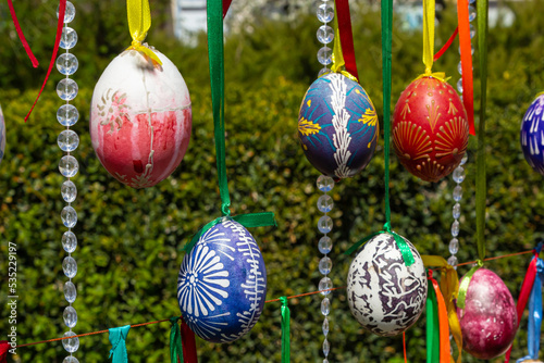 Painted eggs hang from the branches of the Easter tree. The focus is on a yellow egg painted by children by hand.