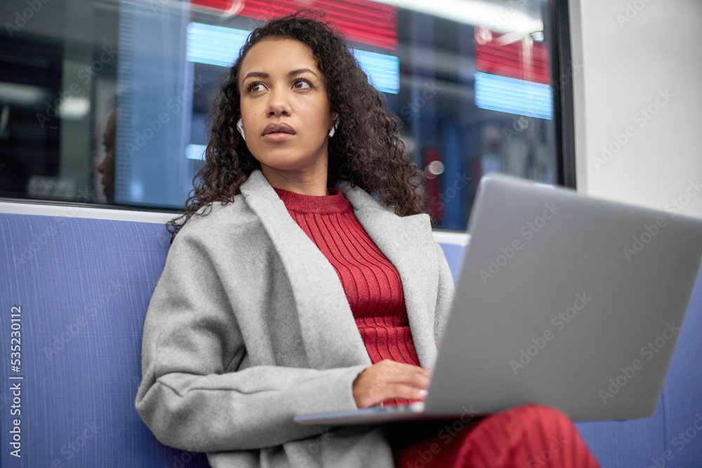 young woman with a laptop traveling in the subway.