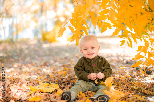 A little boy plays in the autumn park in yellow leaves. Autumn mood