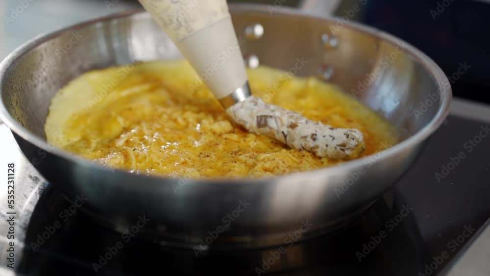 chef puts porcini mushroom dressing on omelette in metal pan in loft style kitchen chef puts porcini mushroom dressing on omelette in metal pan in loft style kitchen