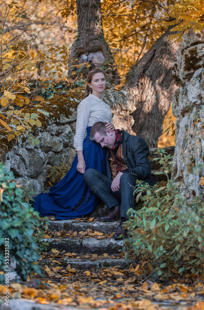 Vampire man wearing victorian suit with vampire woman in the autumn forest. Vintage medieval concept style. Vampire man wearing victorian suit with vampire woman in the autumn forest. Vintage medieval concept style.