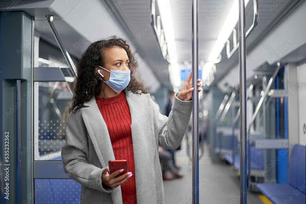 young woman in a protective mask reading a text message in a subway car. young woman in a protective mask reading a text message in a subway car.