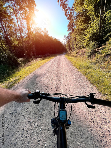 Close up of bicycle handle bar. First-person view of bicycle riding. Man riding a bike. Holding bike handlebar with one hand. Summertime outdoor leisure sport activity. photo